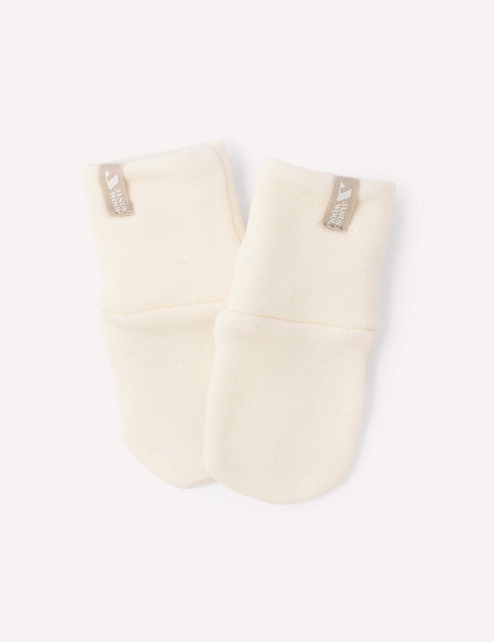 A pair of Mittens – Merino Baby AirWool in a soft marshmallow shade, crafted from merino wool with beige tags, placed side by side on a white background.