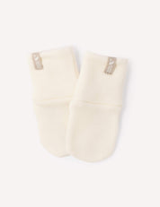 A pair of Mittens – Merino Baby AirWool in a soft marshmallow shade, crafted from merino wool with beige tags, placed side by side on a white background.