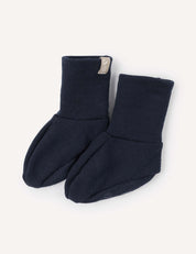 A pair of Booties – Merino Baby AirWool in navy blue, crafted from soft, stretchy fabric with folded cuffs, displayed on a light background.