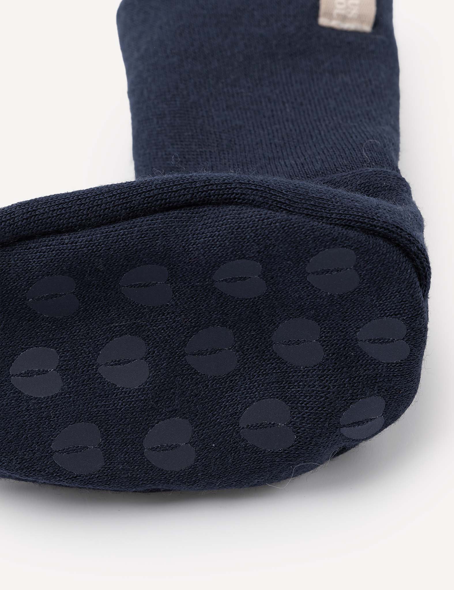 Close-up of the sole of a Booties – Merino Baby AirWool in dark blue, featuring round, grippy rubber dots on the bottom for slip resistance. The textured fabric looks soft and cozy.