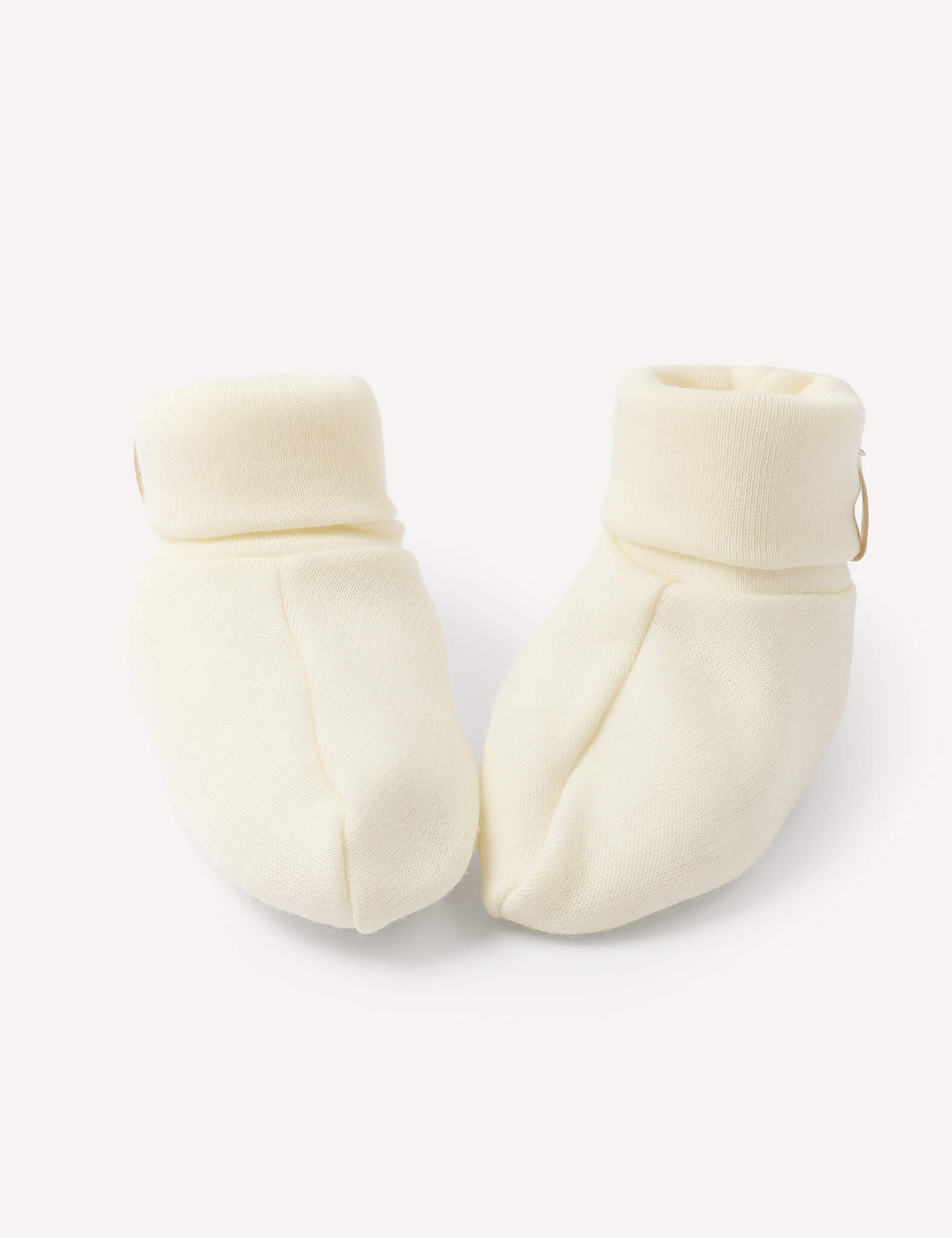 A pair of Booties – Merino Baby AirWool in Marshmallow, crafted from soft knit merino wool with folded cuffs, placed side by side on a plain white background.
