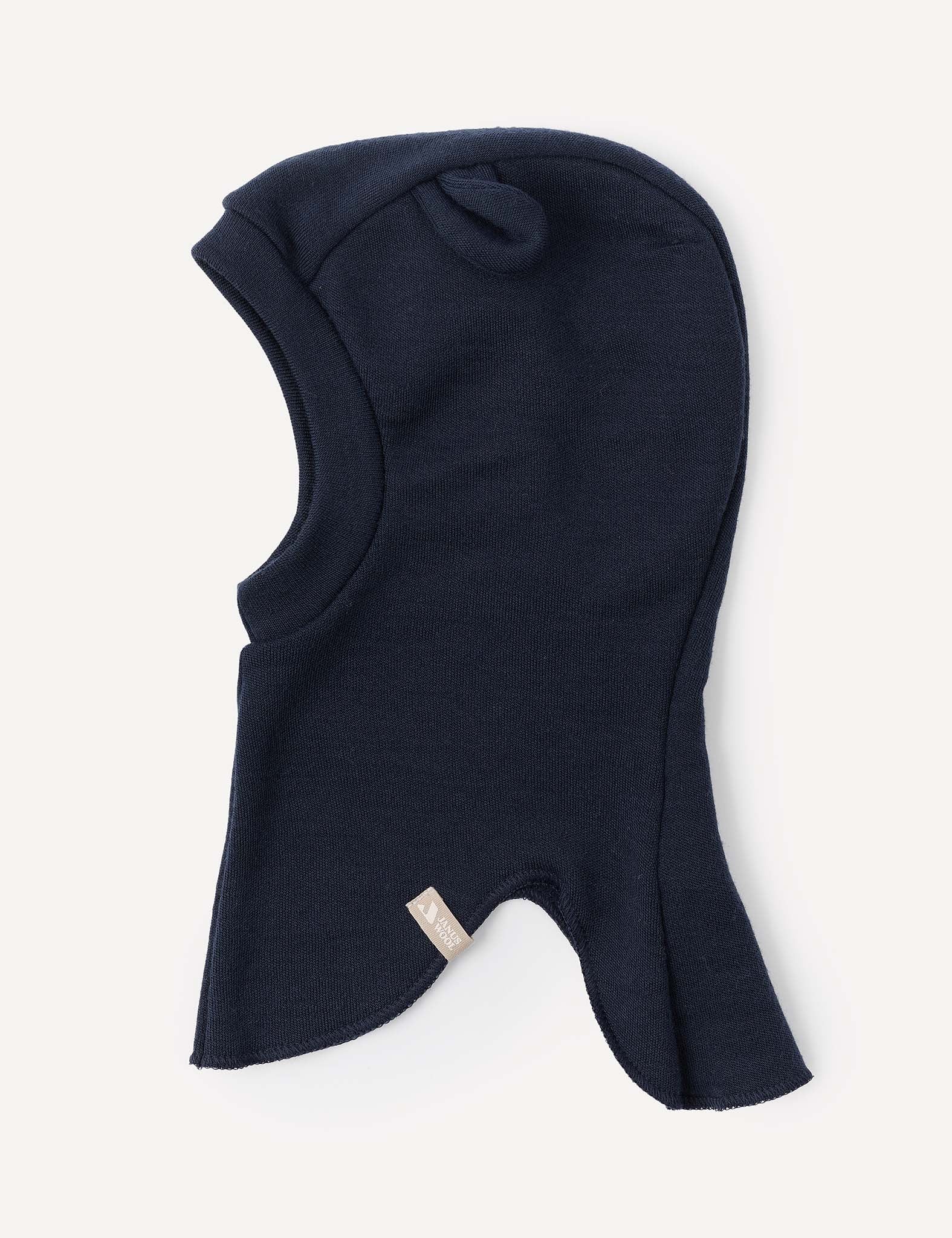 The Balaclava – Merino Baby AirWool is a dark navy blue knit hood crafted from merino wool, featuring a small fabric tag on the side and shown laid flat against a light background.