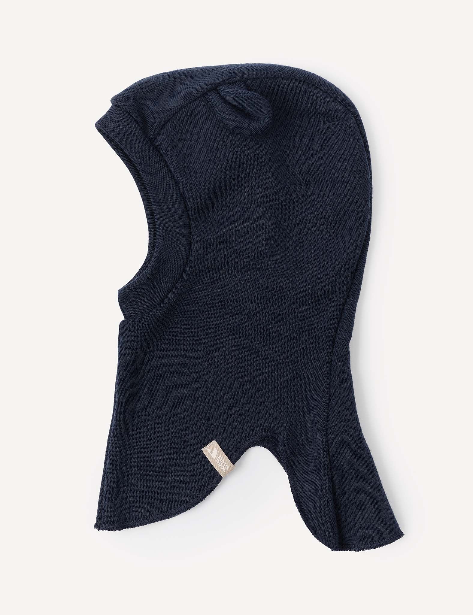 The Balaclava – Merino Baby AirWool is a dark navy blue knit hood crafted from merino wool, featuring a small fabric tag on the side and shown laid flat against a light background.