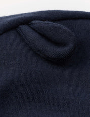 Close-up of the navy blue Merino Baby AirWool Balaclava, showcasing its soft knit fabric with a small, rounded, ear-like detail sewn onto the surface. Crafted from breathable merino wool for gentle comfort.