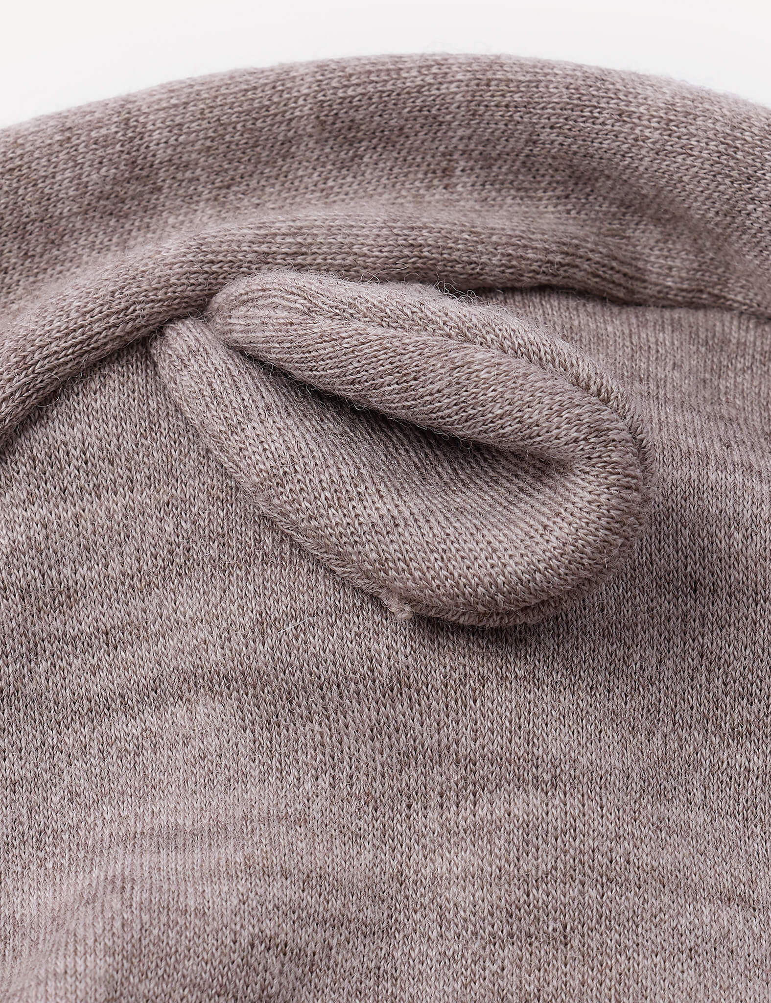 A close-up of the Balaclava – Merino Baby AirWool, a knitted brown hat featuring a small, soft, rounded ear sewn on top to resemble an animal ear, designed as breathable headwear, shown against a plain background.