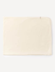 A neatly folded, light beige rectangular Blanket – Merino Baby AirWool made from soft merino wool, featuring a small tag on the top right corner, placed against a plain white background.