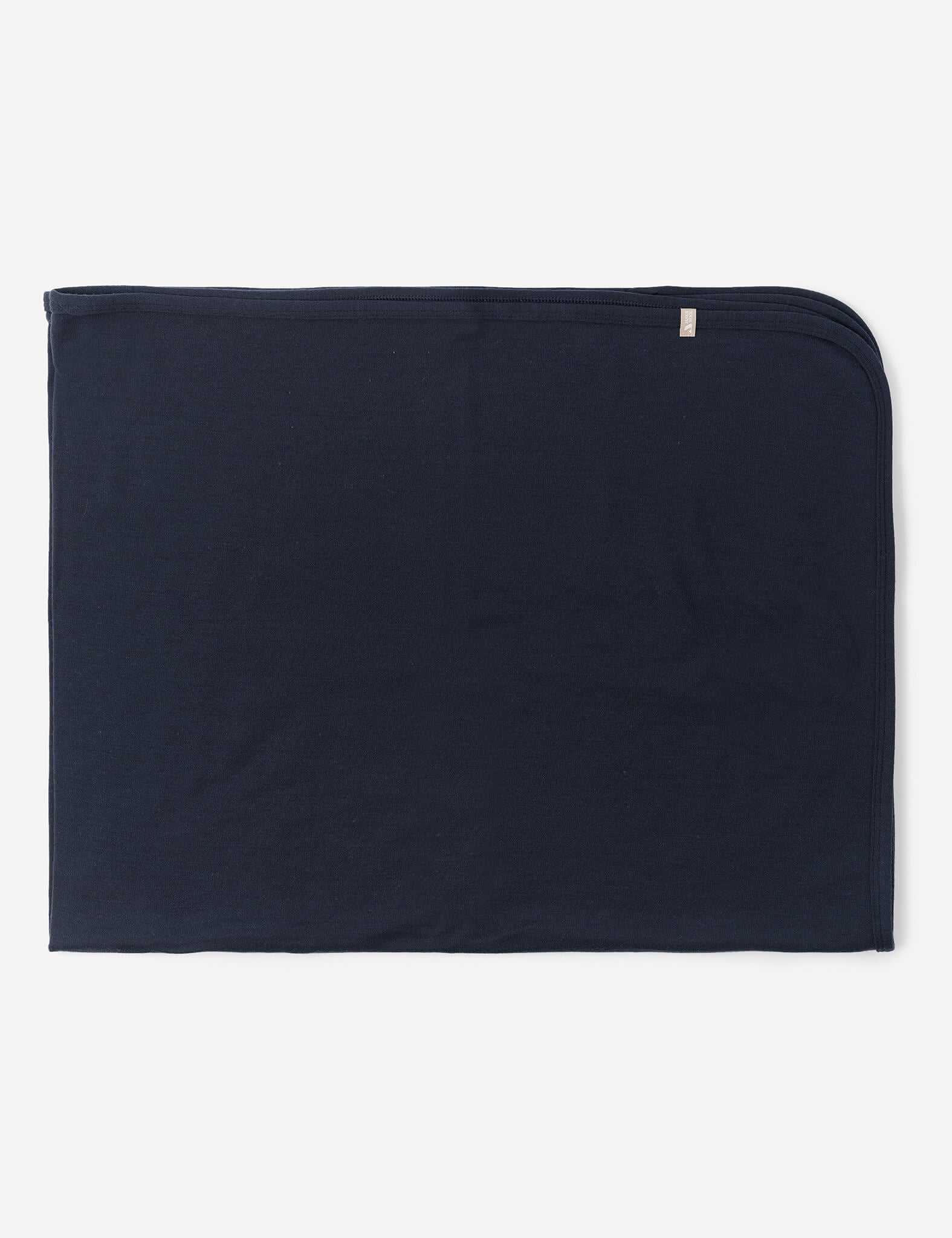 A neatly folded, rectangular Blanket – Merino Baby AirWool in dark navy blue, crafted from soft merino wool with rounded corners on one side, is lying flat against a white background.