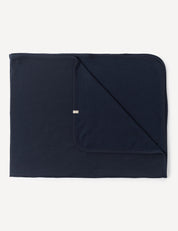 A neatly folded Blanket – Merino Baby AirWool in Navy with one corner flipped to display both sides. The blanket has rounded edges and a small tag on the edge of the folded corner.