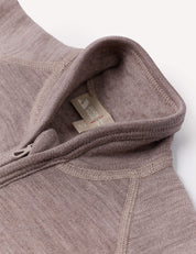 Close-up of the Jacket – Merino Baby AirWool in taupe, crafted from soft, textured fabric and featuring detailed stitching, a zipper, collar, and an interior fabric tag. This zip-up garment provides breathable insulation for enhanced comfort.
