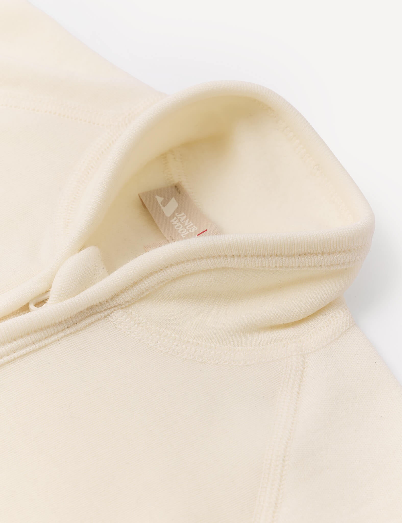 Close-up of the Jacket – Merino Baby AirWool in cream, featuring a high collar, visible stitching, and an interior fabric tag with partially visible text.