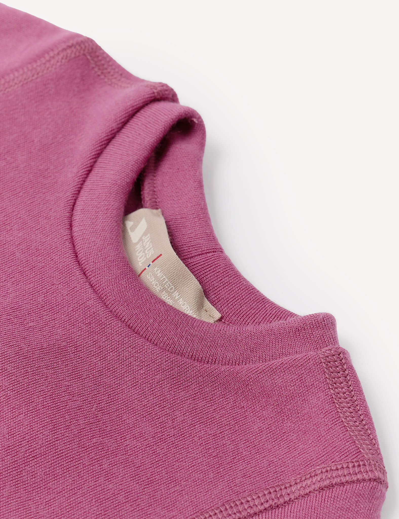 Close-up of the collar and tag on the Body – Merino Baby AirWool sweatshirt in mauve or purple, highlighting the breathable merino fabric’s texture and fine stitching details. The label is partially visible inside the neckline.