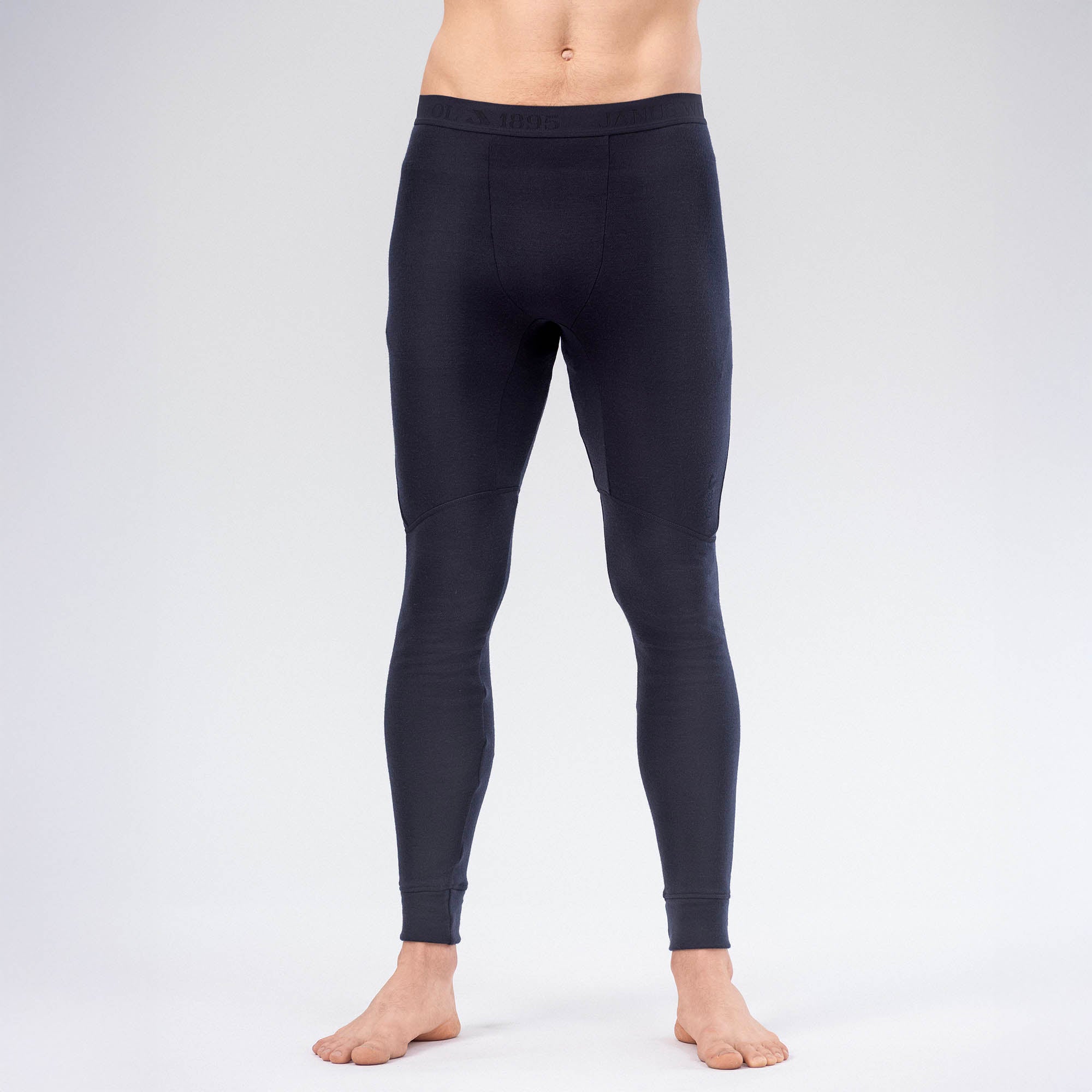 A person is wearing fitted Leggings Merino – AirWool 260 Men, which provide warmth and breathability, standing barefoot against a plain, light background. The image is cropped at the waist and ankles.