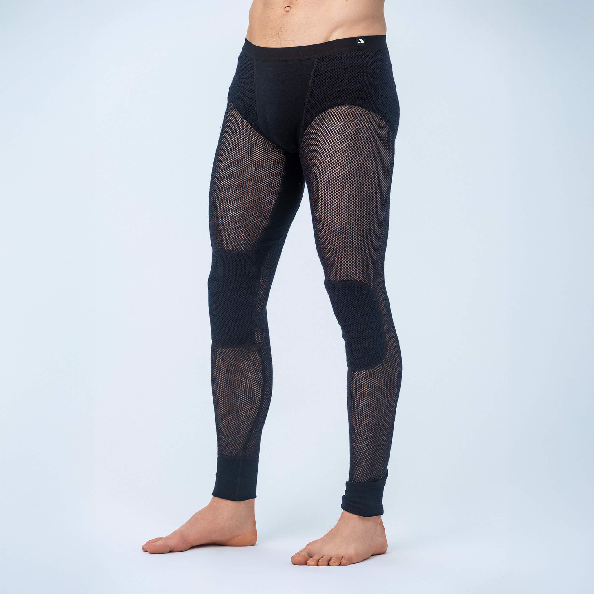A person is barefoot against a light background, wearing Norse Merino 165 Unisex Leggings Mesh—black, full-length leggings featuring mesh panels on the thighs and calves for moisture transport.