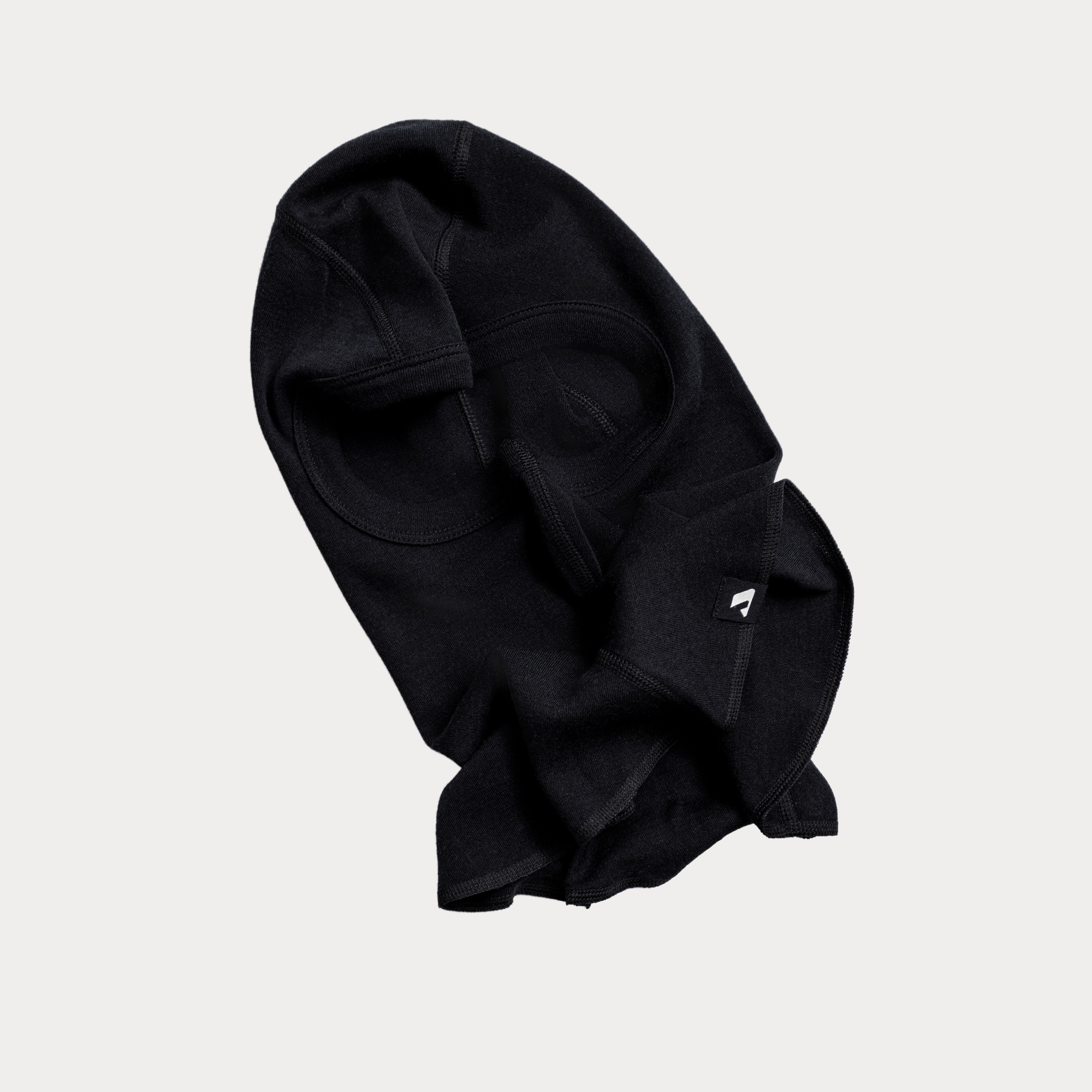 The Balaclava - Norse Merino 220, a black dog sweater with two leg openings and a small tag for warmth and cold protection, is displayed flat on a light gray background.