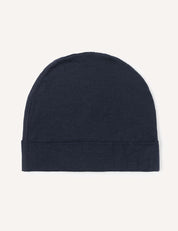 The Beanie – Merino Kids Light, crafted from soft wool in a plain, dark navy blue shade, is displayed flat against a light background. This beanie features a minimalist, seamless design with a folded edge at the bottom.