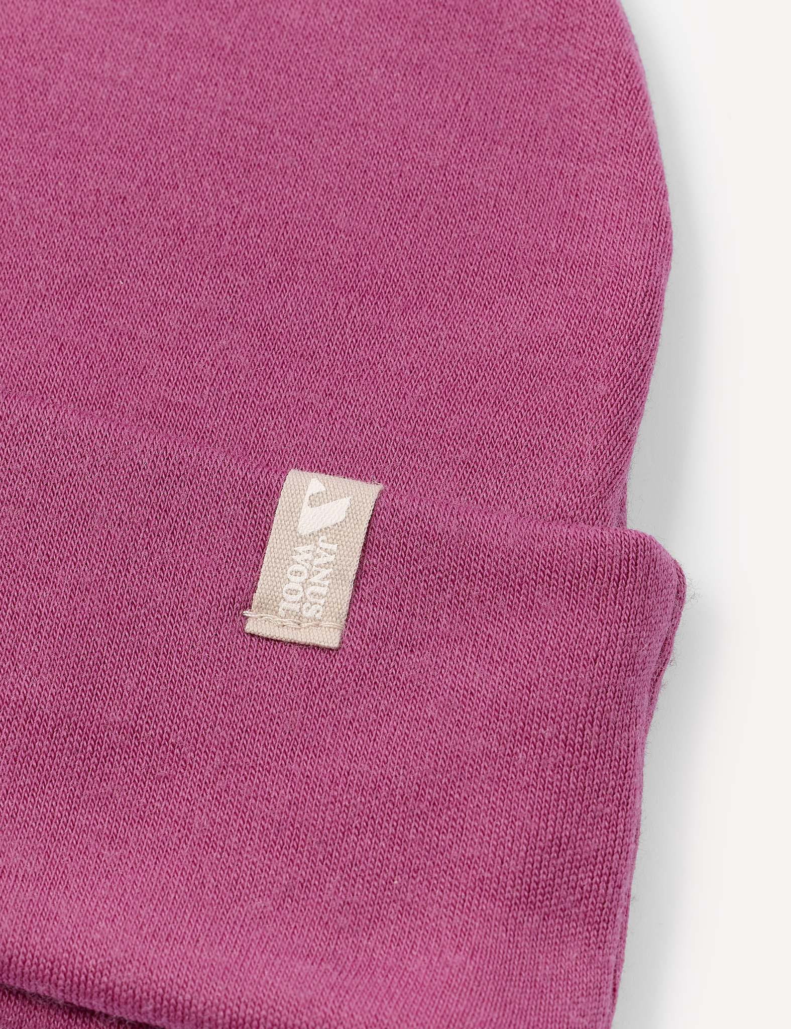 A close-up of the Beanie – Merino Kids AirWool in purple, featuring a small white fabric tag. This extra warm and breathable accessory is perfect for keeping kids comfortable on chilly days.