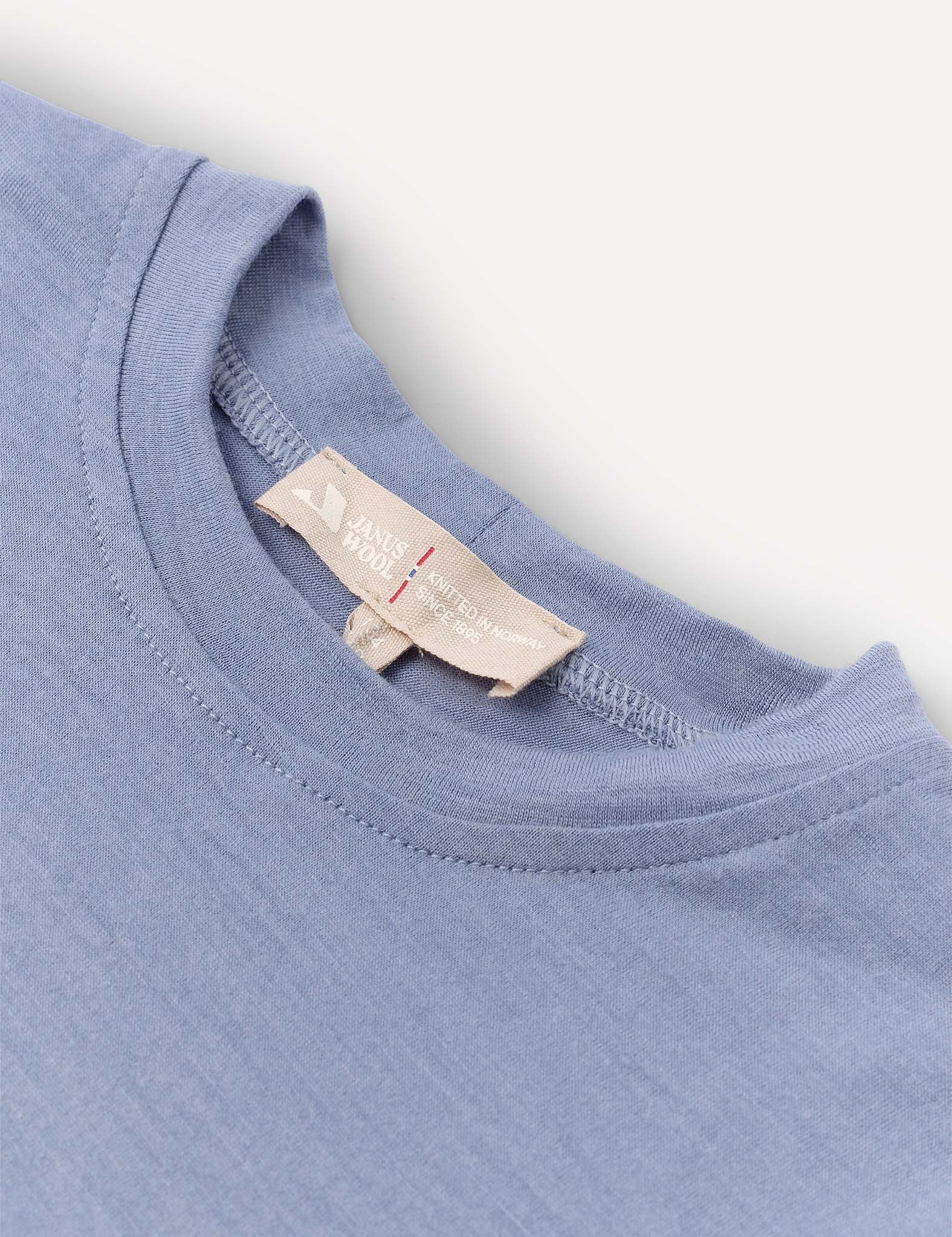 A close-up of the Crewneck – Merino Kids Light, a soft light blue crewneck t-shirt featuring a beige label inside the collar that reads HAND YOUR and LIMITED HANDMADE EDITION, laid flat on a light background.