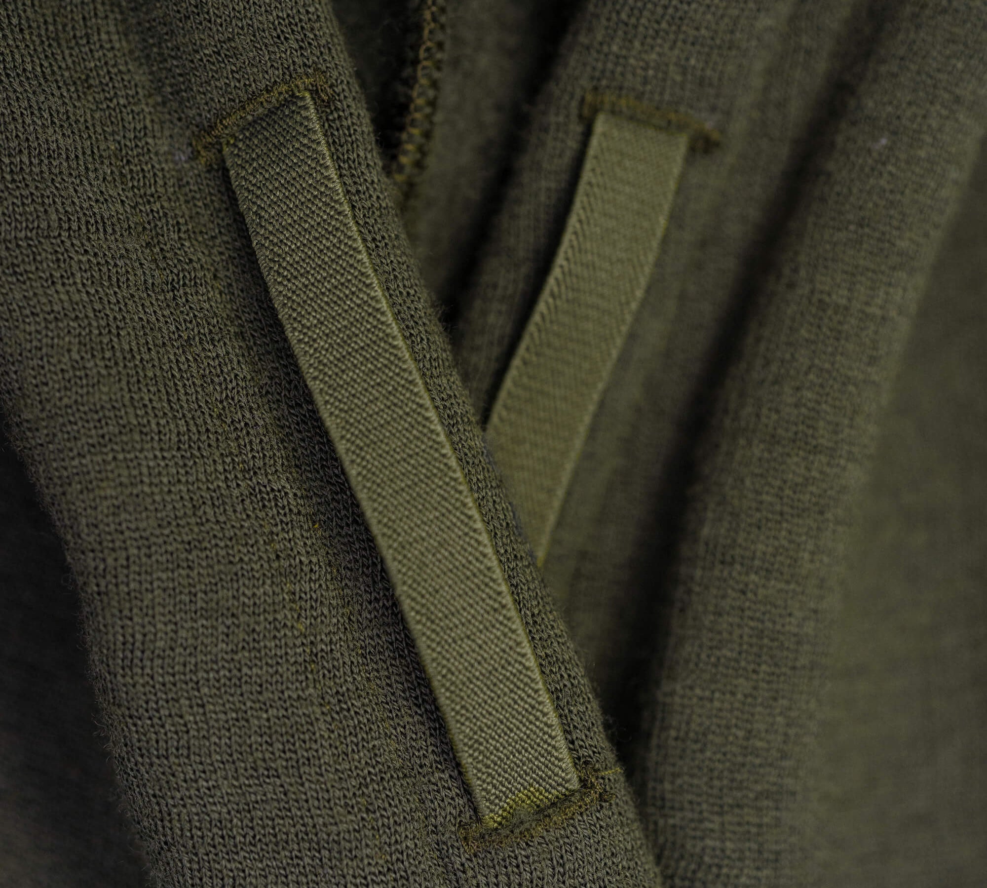 Close-up of the Hoodie Merino – AirWool 280 Women in olive green, featuring two drawstrings over its soft, insulating merino wool knit—ideal for cool to cold weather and showcasing the detailed fabric texture.