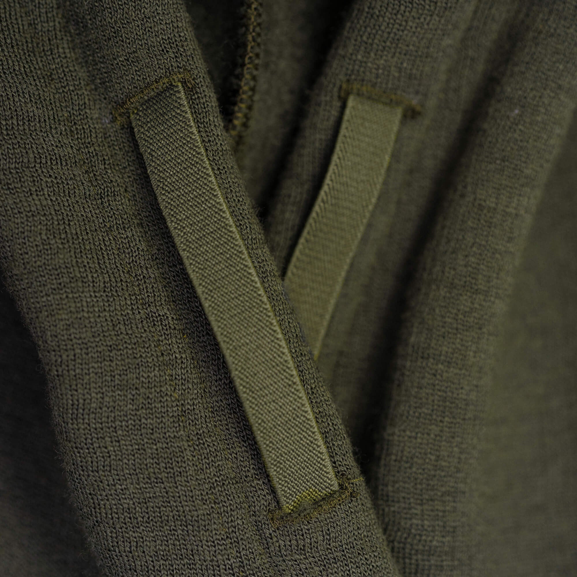 Close-up of the Hoodie Merino – AirWool 280 Women in olive green, featuring two drawstrings over its soft, insulating merino wool knit—ideal for cool to cold weather and showcasing the detailed fabric texture.