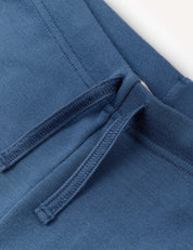 Close-up of a pair of blue Flarepants – Merino Kids AirWool, highlighting the waistband area with visible drawstrings and detailed stitching.