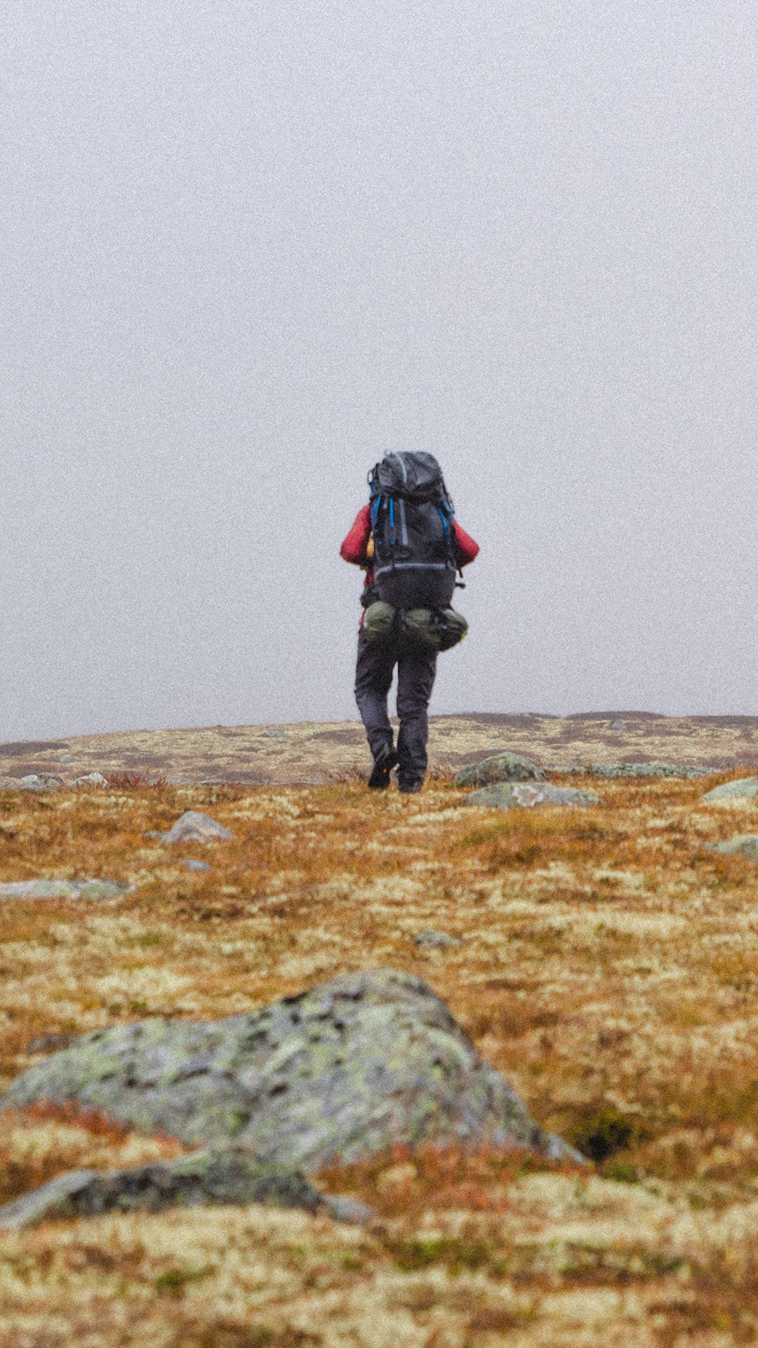 Mann på fjell med Janus ullundertøy, farge rød