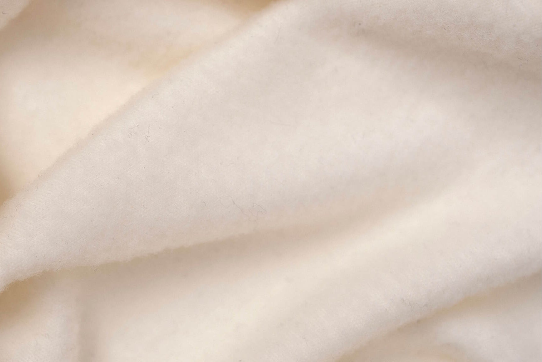 Close-up of the Polo Zip Merino – AirWool 260 Women shows its cream-colored, soft, and fuzzy merino wool fabric with gentle folds—breathable and smooth for cozy warmth and comfort.