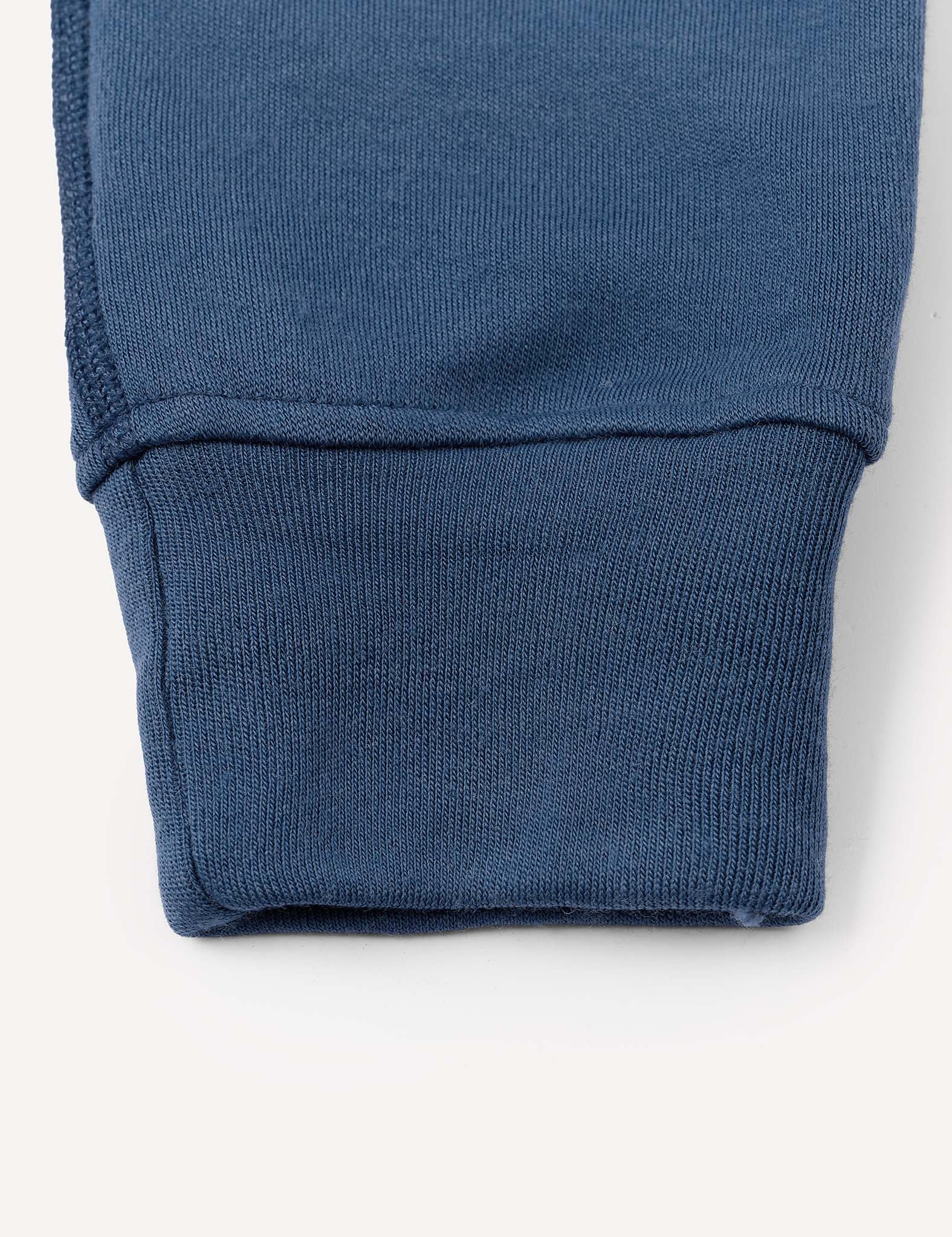 Close-up of the cuff of a blue ribbed sleeve, highlighting the texture and stitching details of the Sweatpants – Merino Kids AirWool against a plain light background, evoking the cozy feel these warm sweatpants provide.