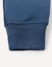 Close-up of the cuff of a blue ribbed sleeve, highlighting the texture and stitching details of the Sweatpants – Merino Kids AirWool against a plain light background, evoking the cozy feel these warm sweatpants provide.