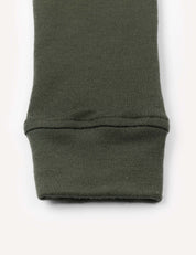 Close-up of the cuff of an olive green knit sleeve, laid flat on a light background. The fabric appears warm and soft, with a slightly ribbed texture at the cuff, characteristic of Leggings – Merino Kids AirWool.