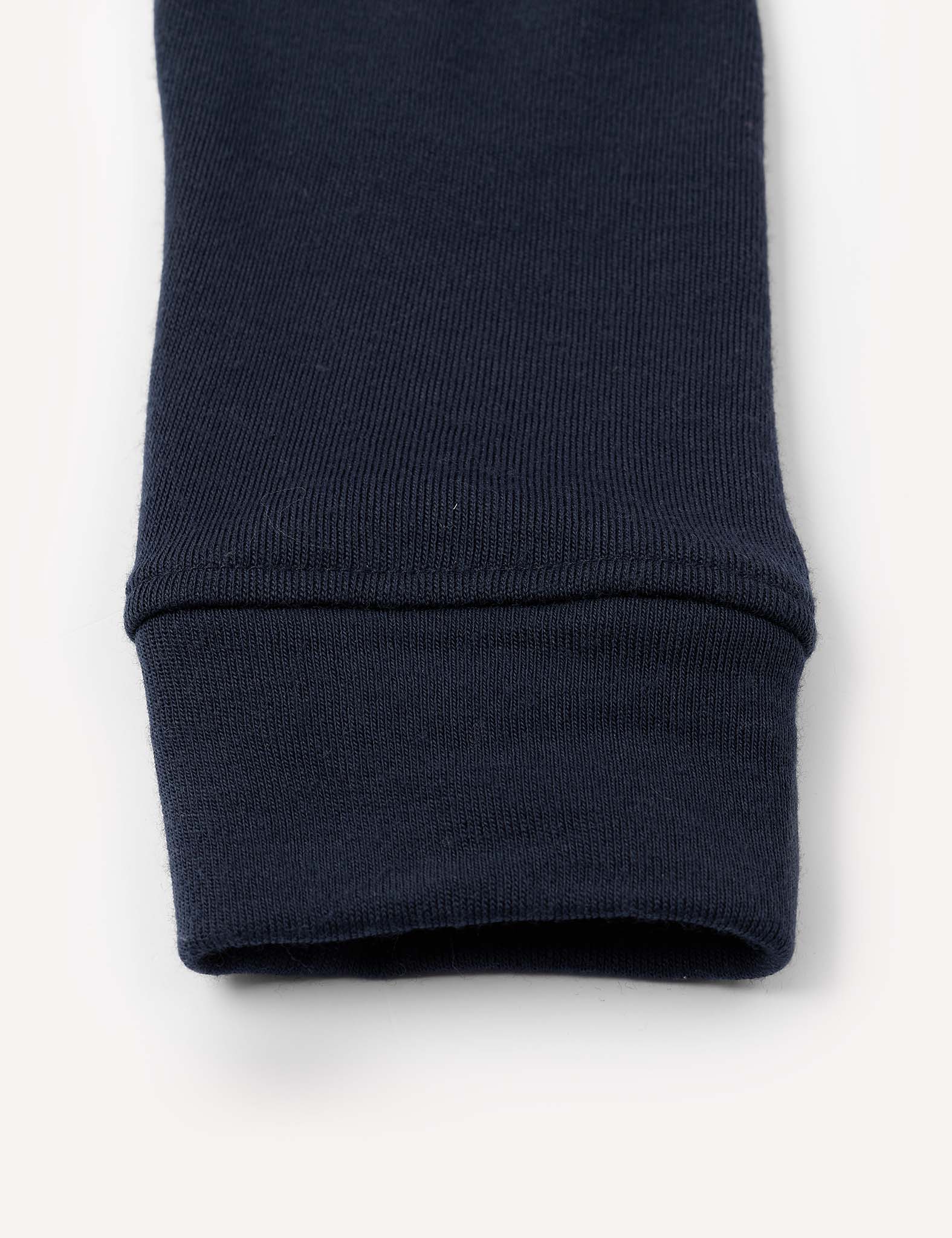 Close-up of the cuff of a navy blue Leggings – Merino Kids AirWool, made of warm brushed AirWool ribbed fabric, laying flat on a white background.