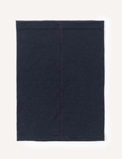 A rectangular black Merino Kids Light Neckwarmer made from merino wool, featuring visible stitching down the middle, is laid flat on a light background.
