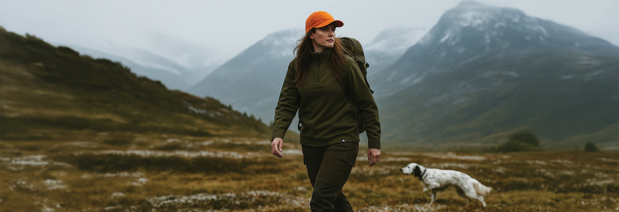 Woman walking with a dog in a mountainous landscape, wearing Janus Wool Norse merino wool polo