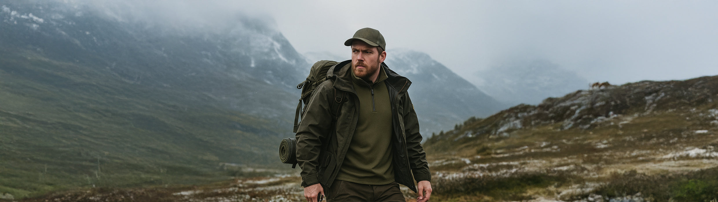 Man in Janus Wool Norse merino polo with a backpack against a mountainous background